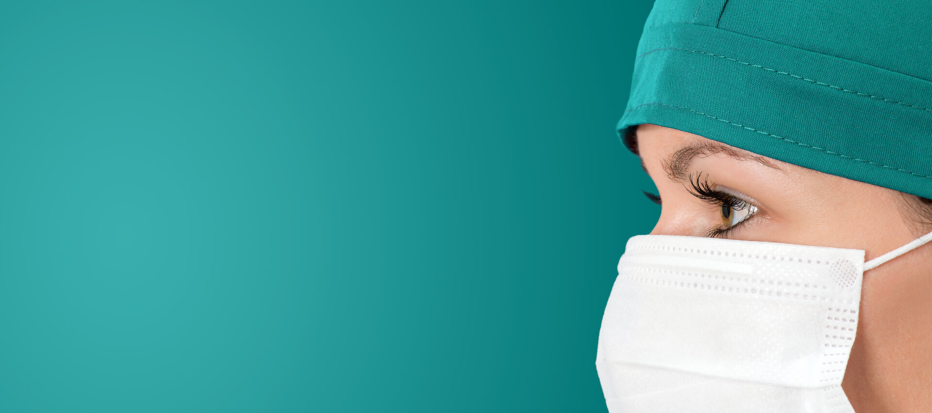 Profesional de salud con mascarilla y gorro quirúrgico mirando hacia la izquierda